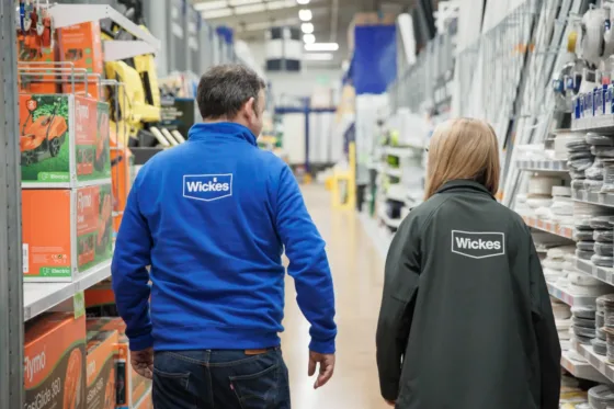 Two workers at Wickes walking down a product aisle in a store
