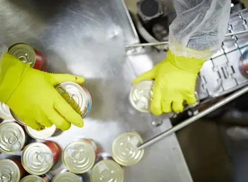 Worker in the food and beverage industry moving cans on a factory line