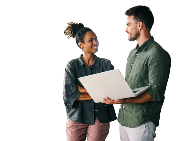 Two colleagues standing by a window, smiling and discussing work while holding an open laptop.