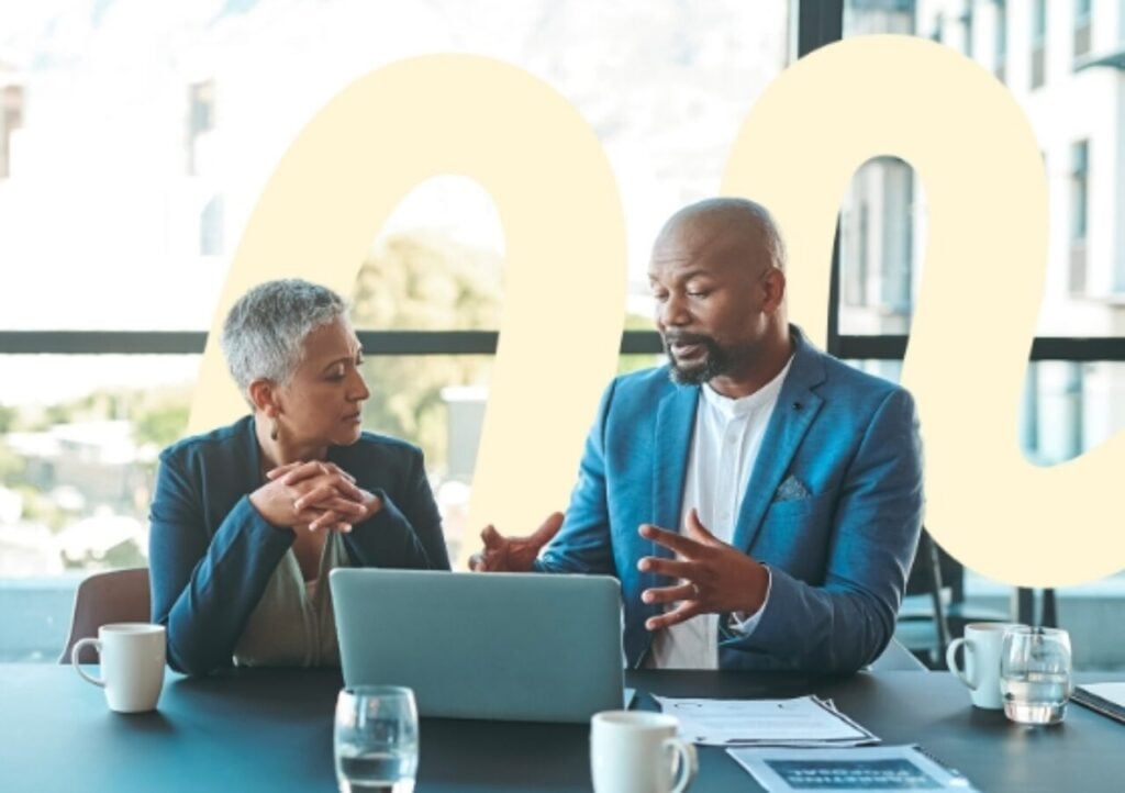 Man and woman engaging in conversation and facing a shared laptop