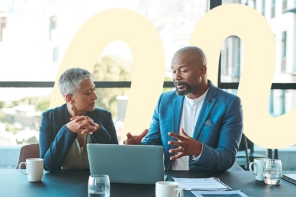 Man and woman engaging in conversation and facing a shared laptop